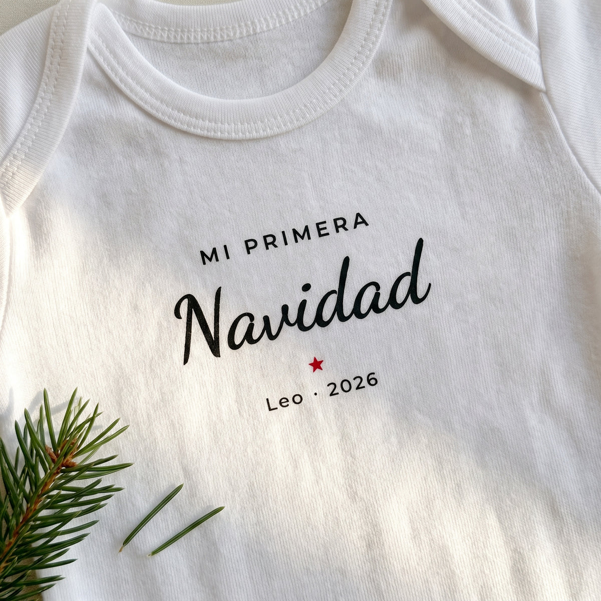 Detalle del estampado en el body: «MI PRIMERA Navidad», una estrella roja y «Leo · 2026»