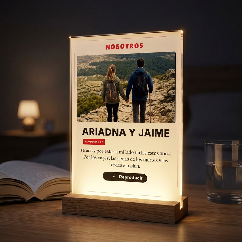 Placa de metacrilato personalizada con vuestra historia en estilo serie encendida sobre la base de madera con luz LED, en una mesilla de noche
