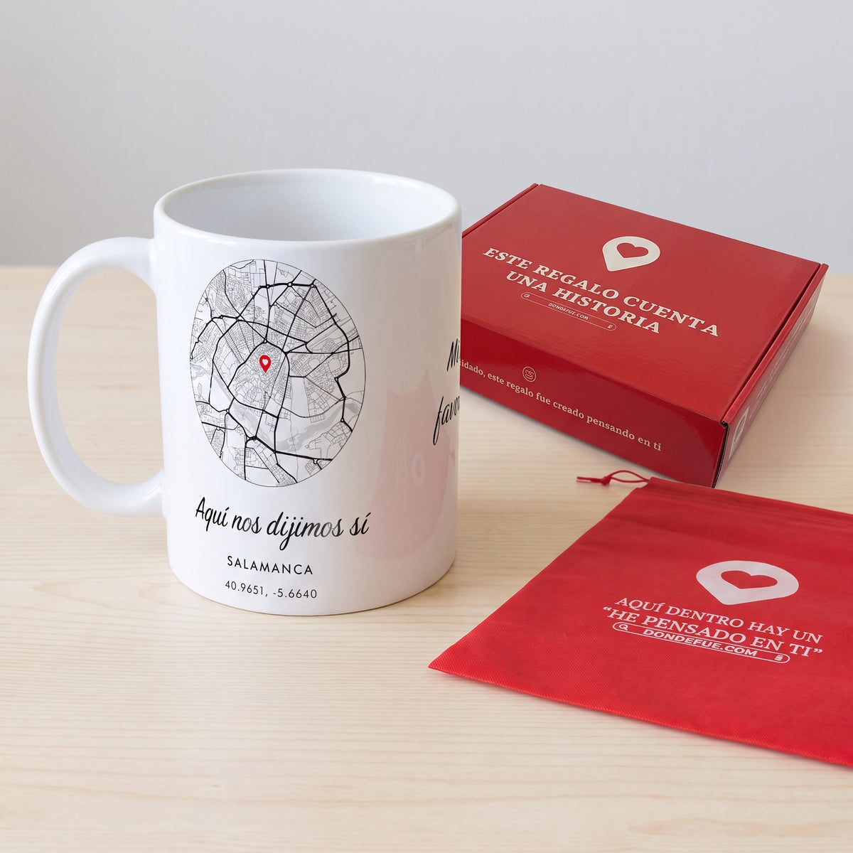 Taza ciudad con el mapa de Salamanca junto a la caja roja y la bolsa de tela roja en que se envía