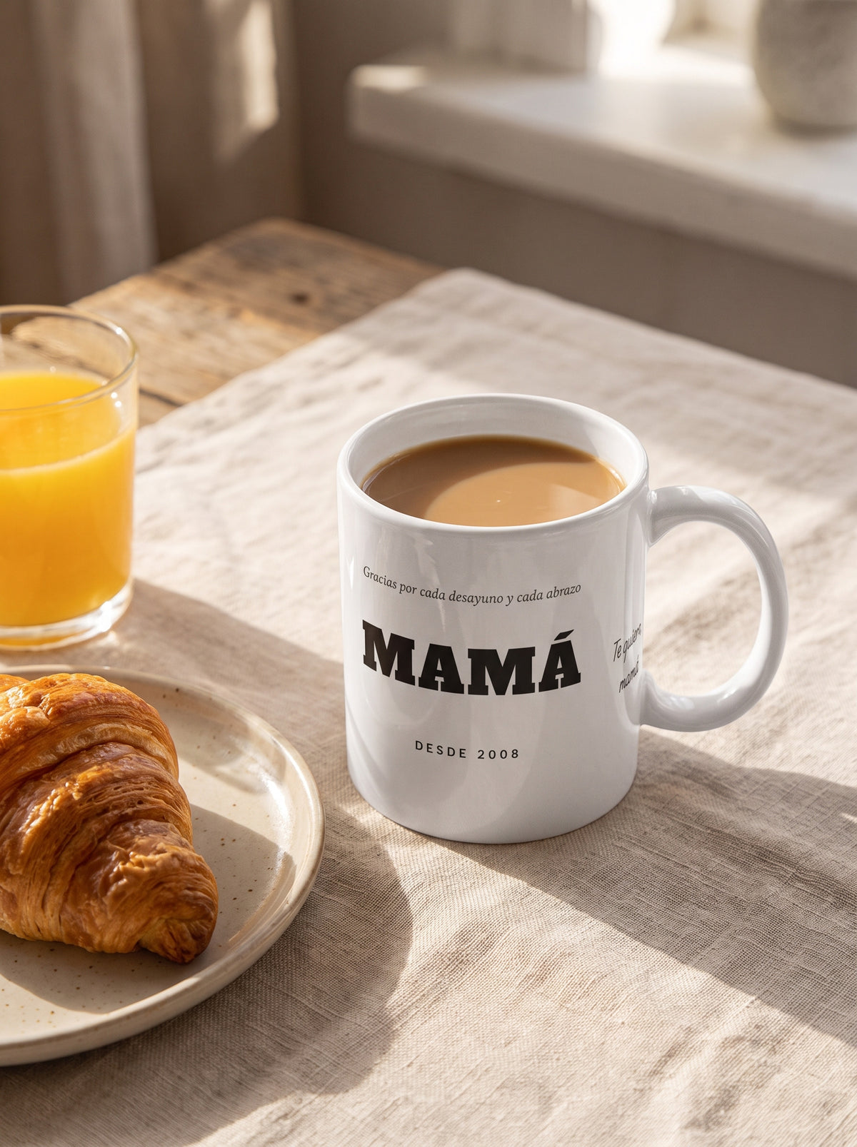 Taza MAMÁ con dedicatoria (Gracias por cada desayuno y cada abrazo · MAMÁ · DESDE 2008 · Te quiero, mamá): en un desayuno con café y cruasán
