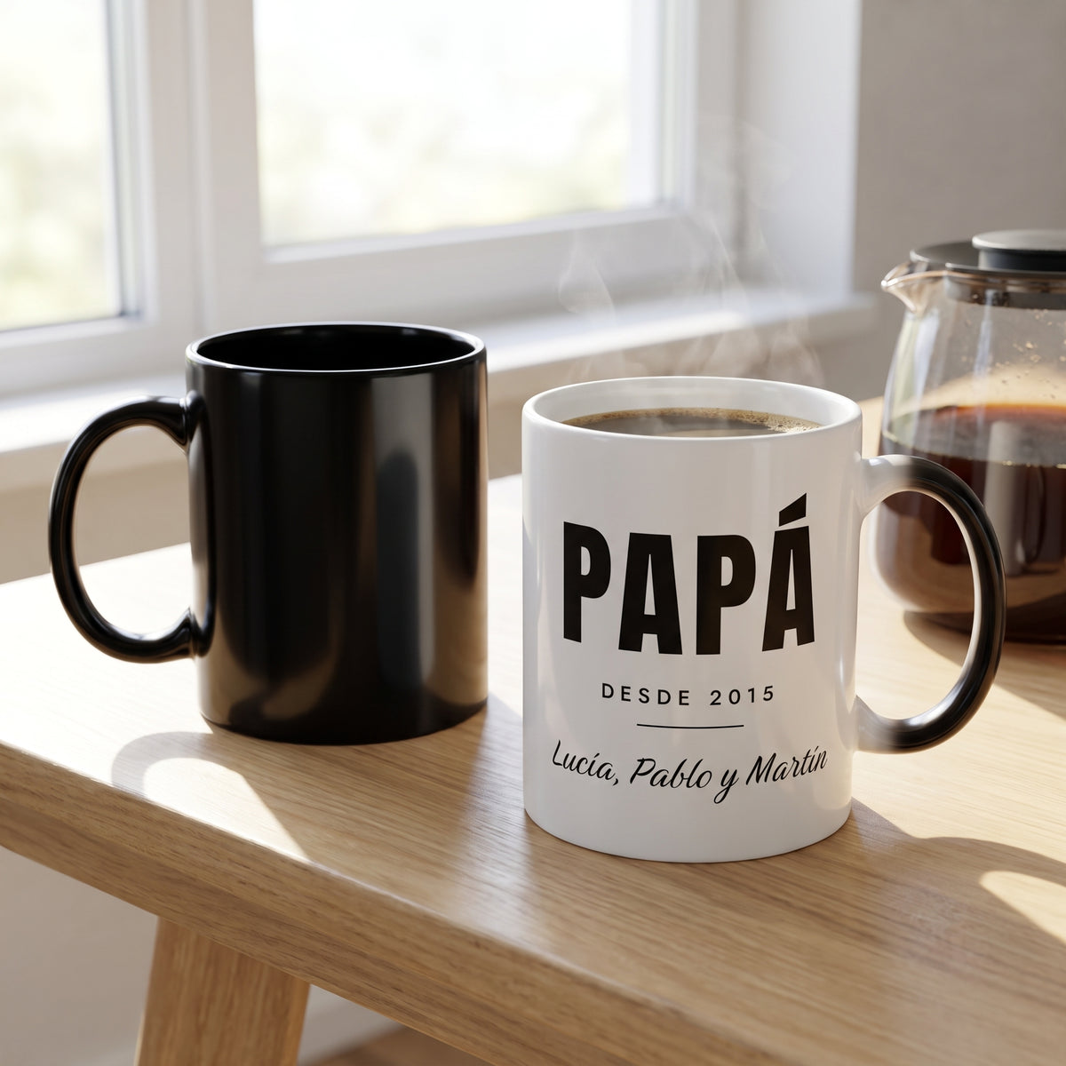 Caneca mágica negra junto a la taza blanca «Papá desde» con el diseño revelado