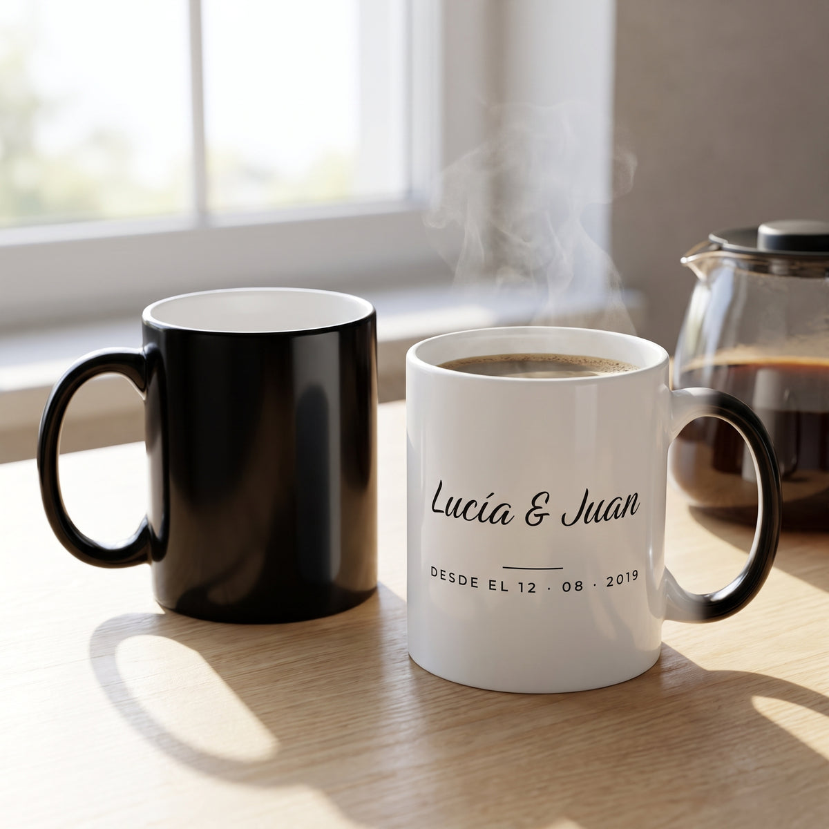 Caneca mágica negra junto a la taza blanca de pareja con los nombres revelados