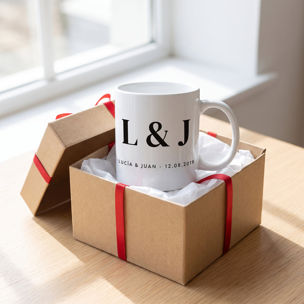 Taza de pareja con iniciales en una caja de regalo con lazo rojo