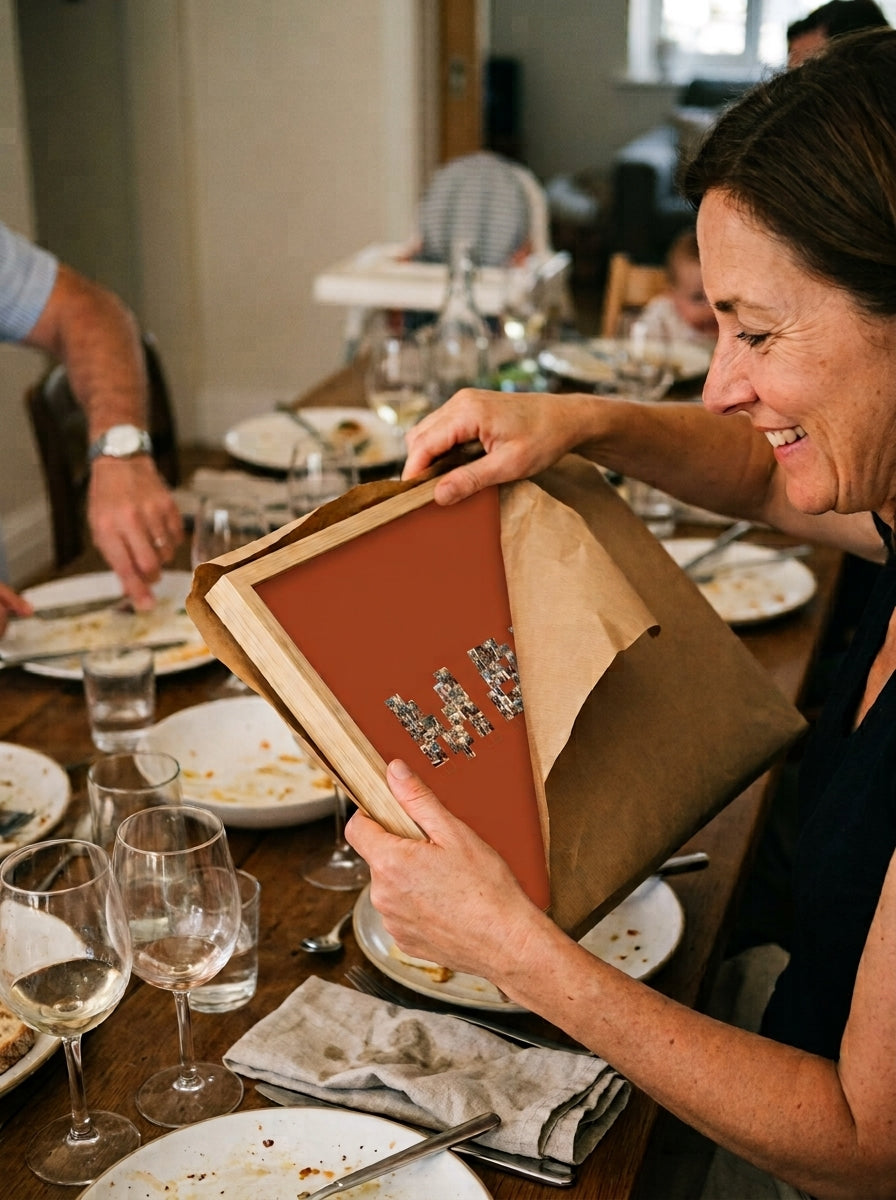 Abriendo el regalo del cuadro nombre con fotos personalizado de bautizo en una comida familiar