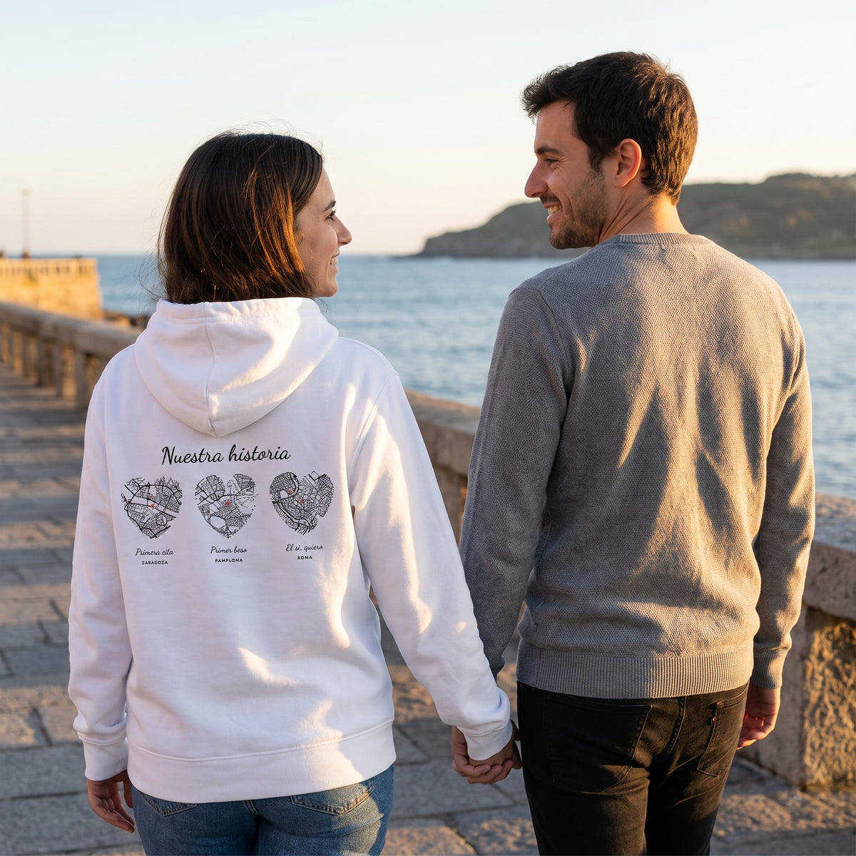 Paseo al atardecer con la sudadera con capucha blanca personalizada con tres mapas en corazón: Zaragoza, Pamplona y Roma estampado en la espalda