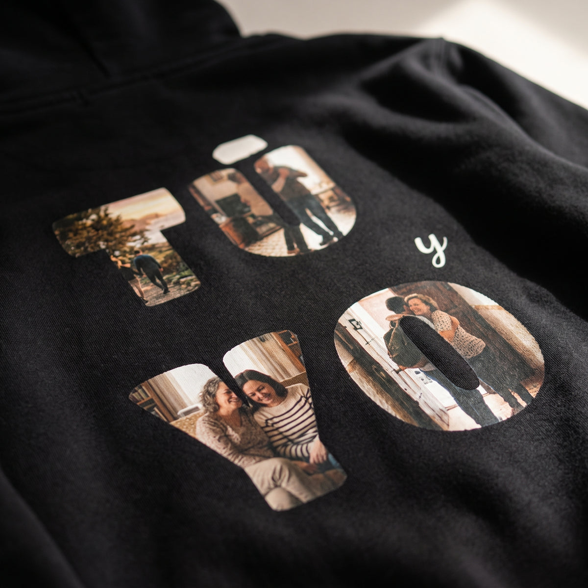 Detalle del estampado DTF de «TÚ y YO» con las letras rellenas de fotos y los nombres Irene & Dani sobre el tejido de una sudadera con capucha negra
