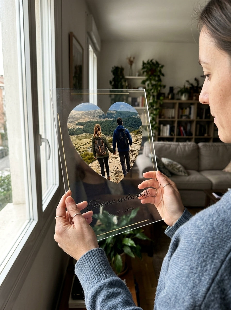 Sosteniendo la placa de metacrilato personalizada con una foto y dedicatoria a contraluz junto a una ventana